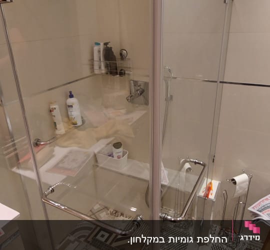 מקלחון זכוכית עם מוצרי טיפוח על מדף